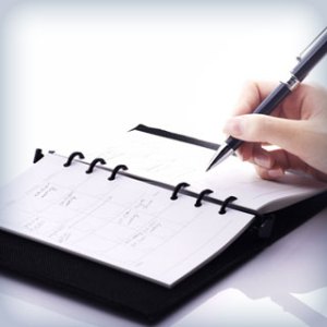 person writing in a date book